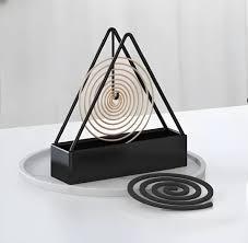 Minimalist black metal incense coil holder with spiral incense on a white tray