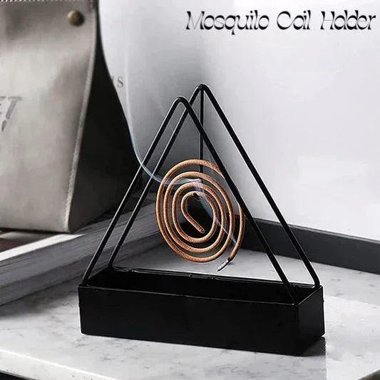 Triangle metal mosquito coil holder with burning coil on a marble tabletop